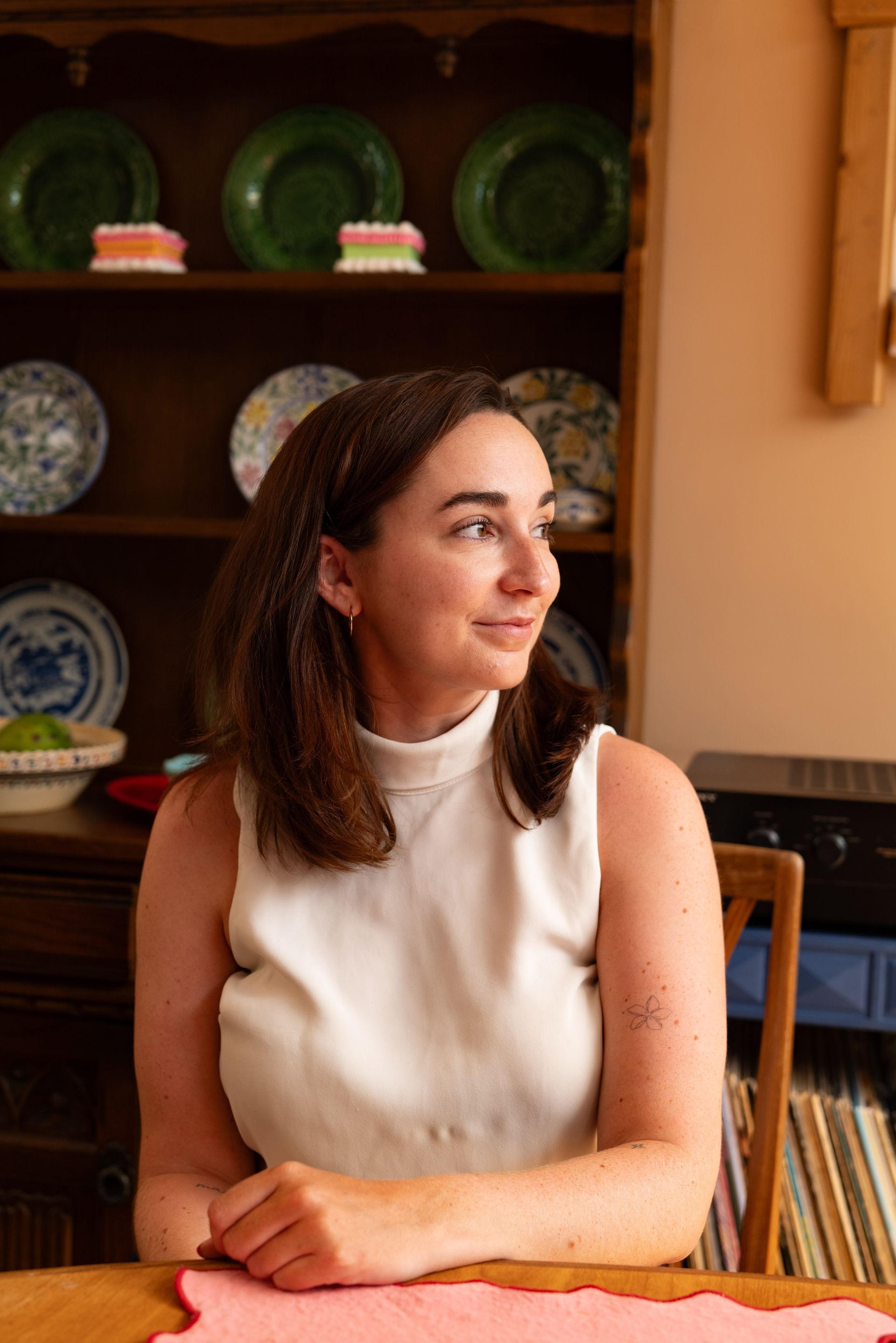 Heather Brazier seated in front of an antique dresser displaying green and blue-and-white plates